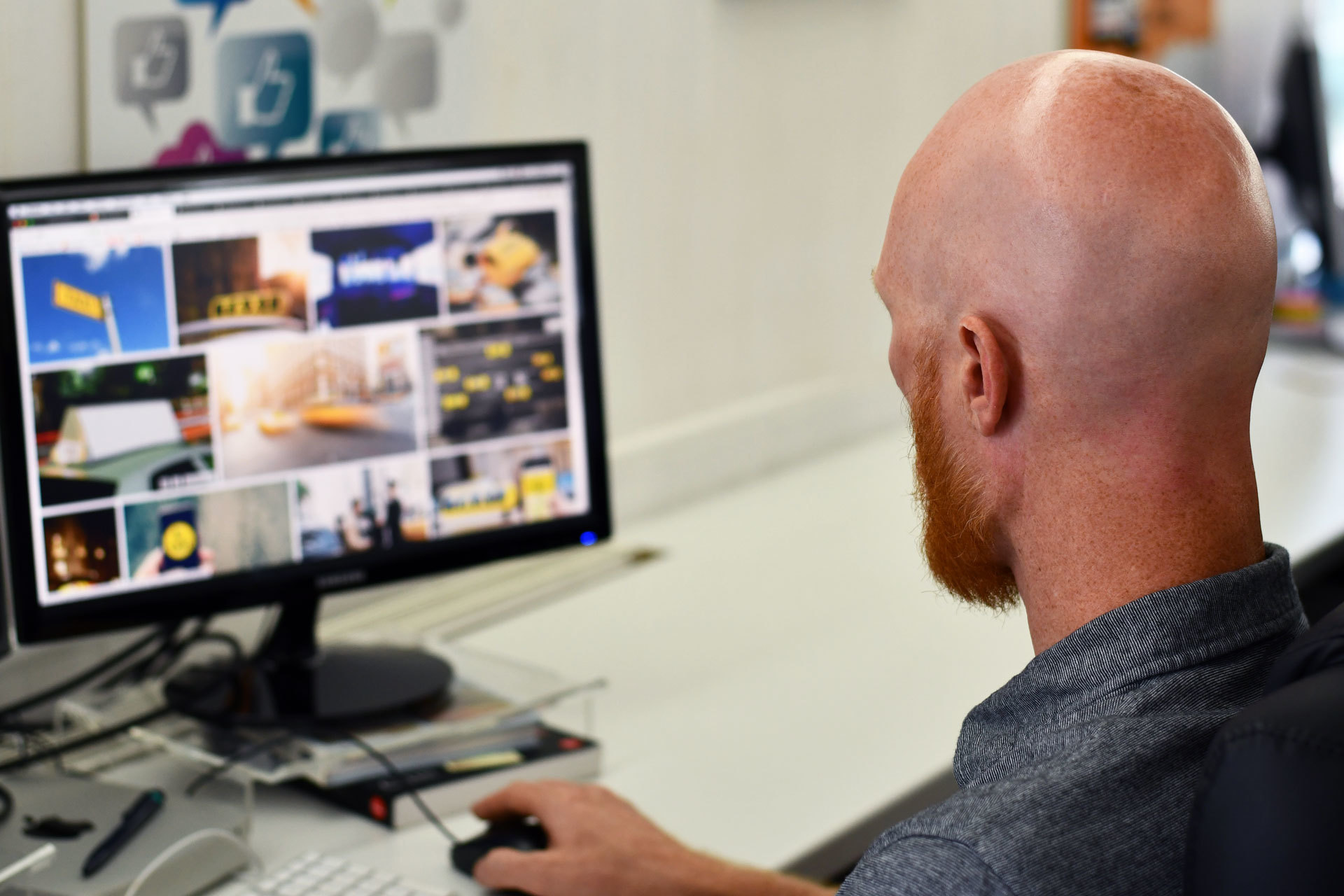 A web designer sat at his desk, creating a new website design on his computer