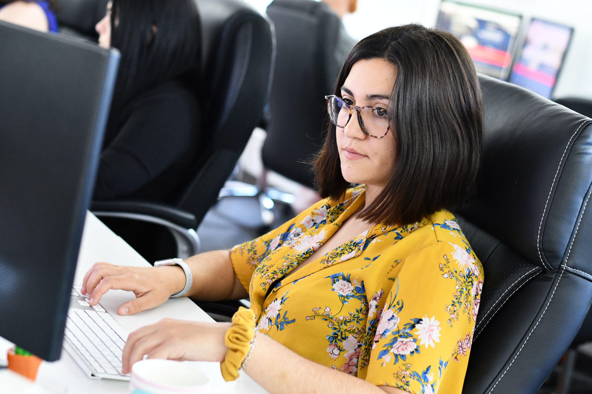A woman sat at a desk working on her desktop computer
