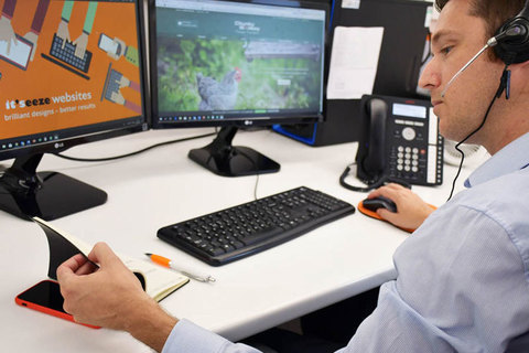 A website support worker wearing a headset flicking through a notebook