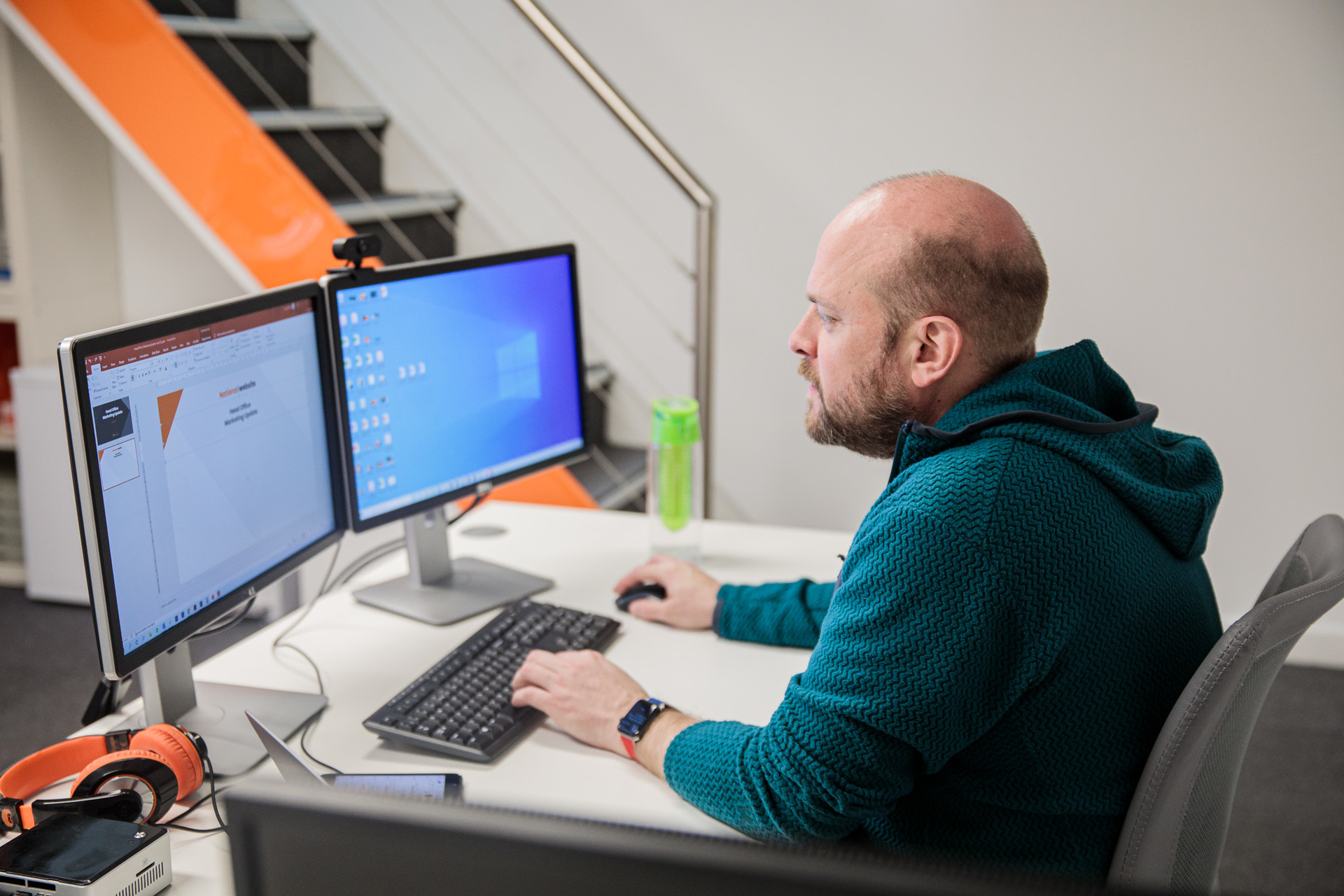 A man sat at his desk concentrating on his desktop computer